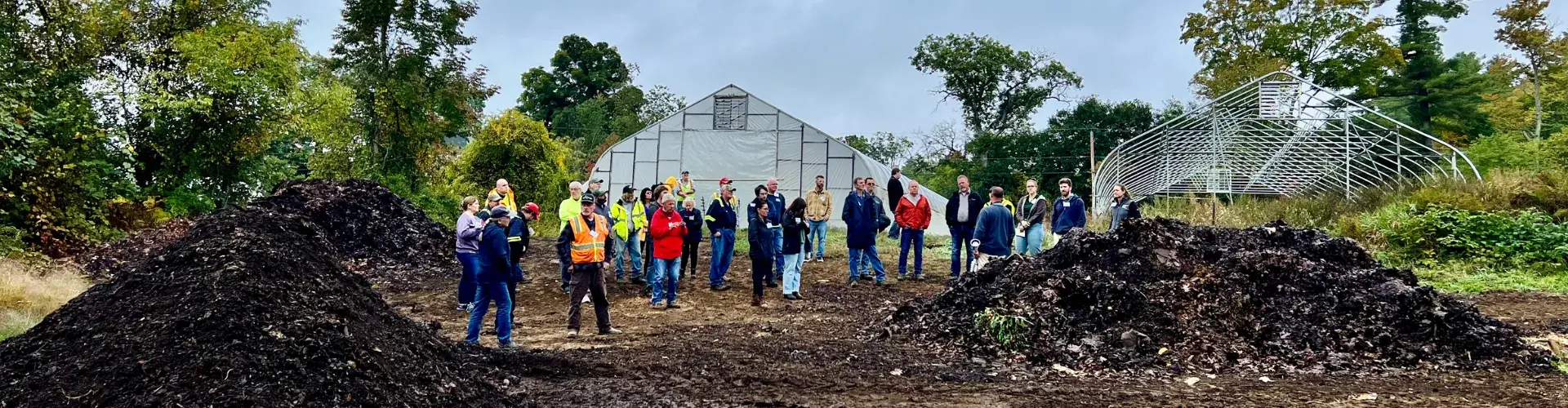 Group of solid waste operators looking at two compost piles