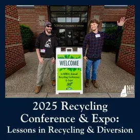 two conference attendees smiling next to welcome sign