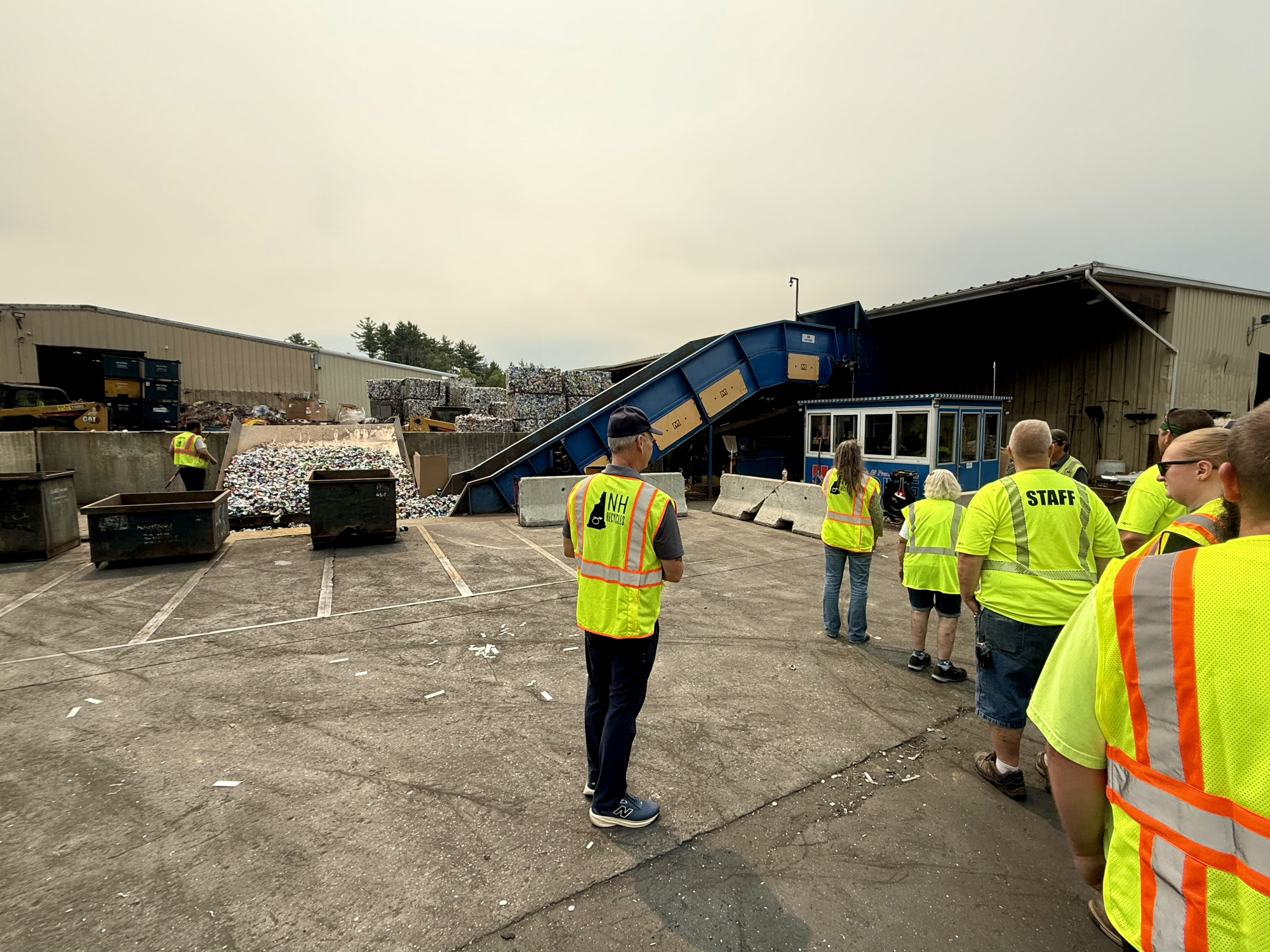 group of people watching an aluminum can baler