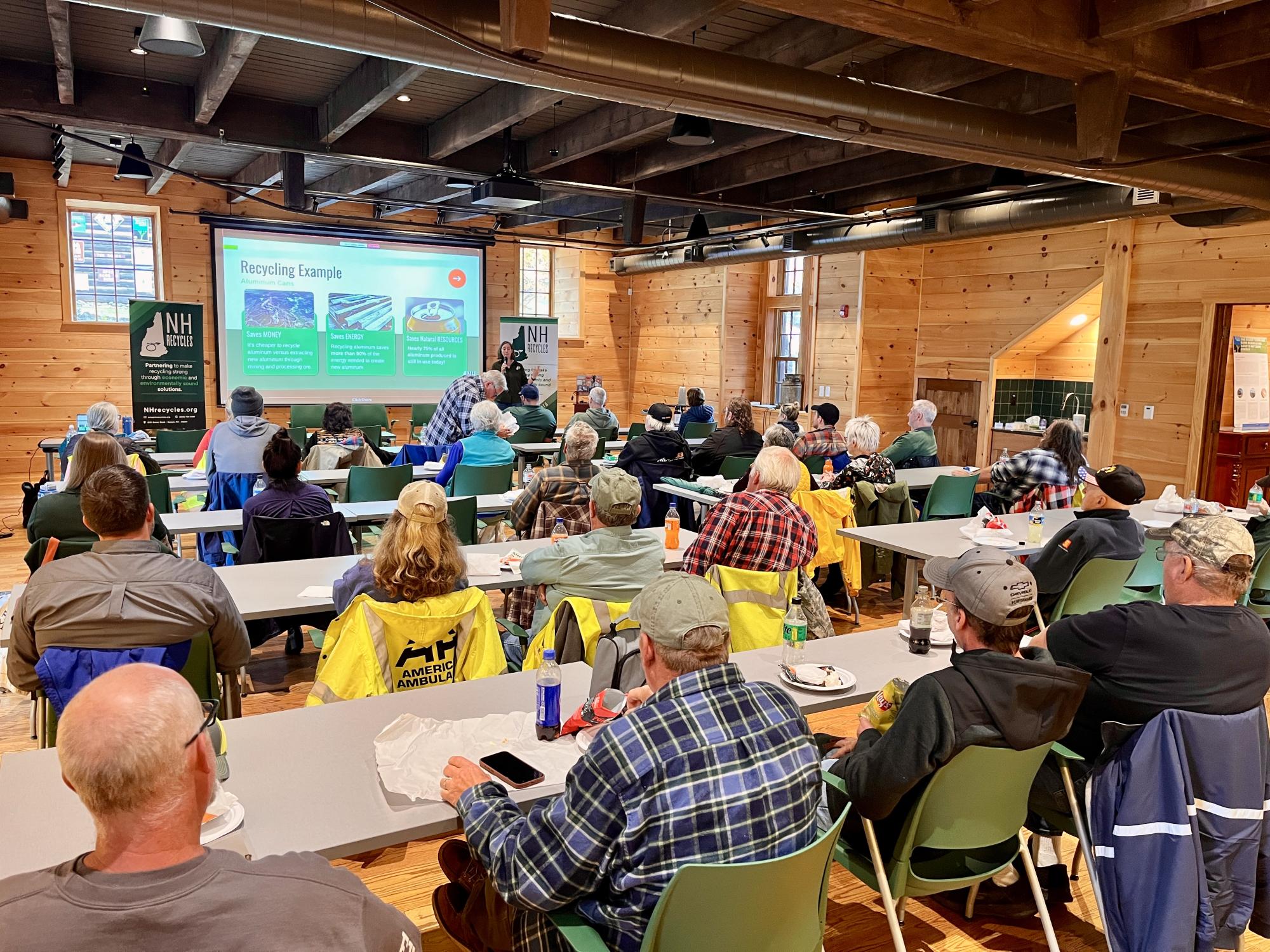 Woman presenting to a full room of attendees about recycling