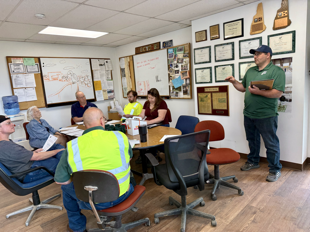 Brian in green shirt speaking to recycling operators sitting at a table