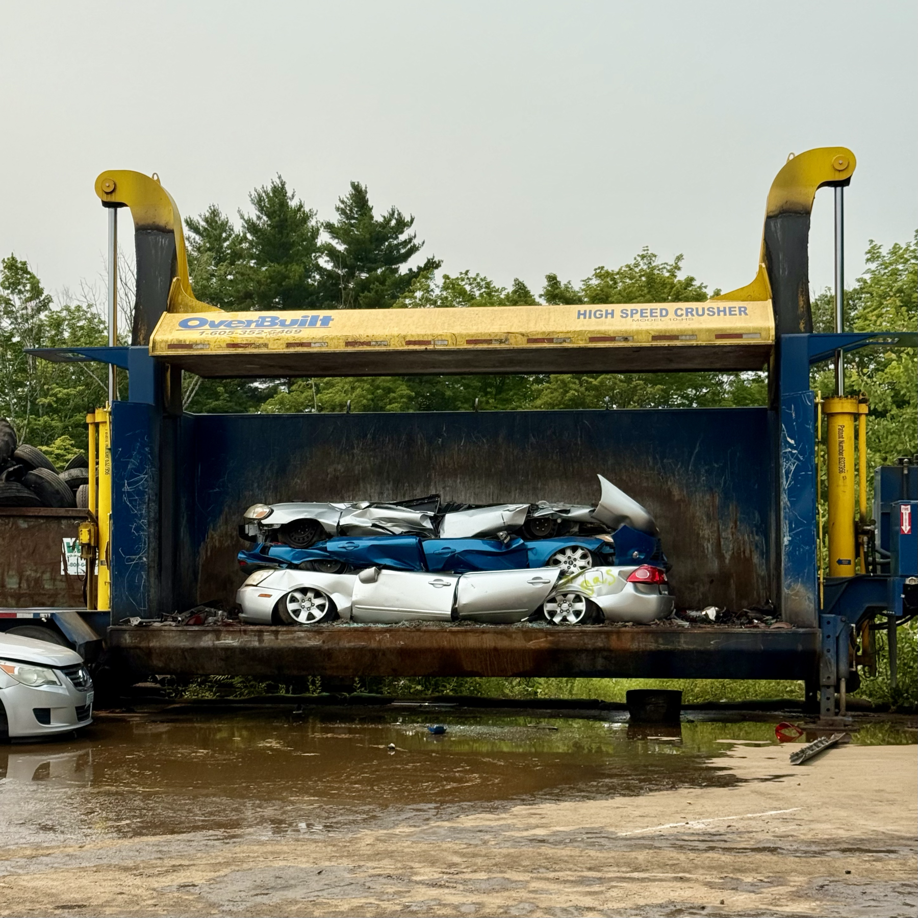 three crushed cars in a car crusher machine