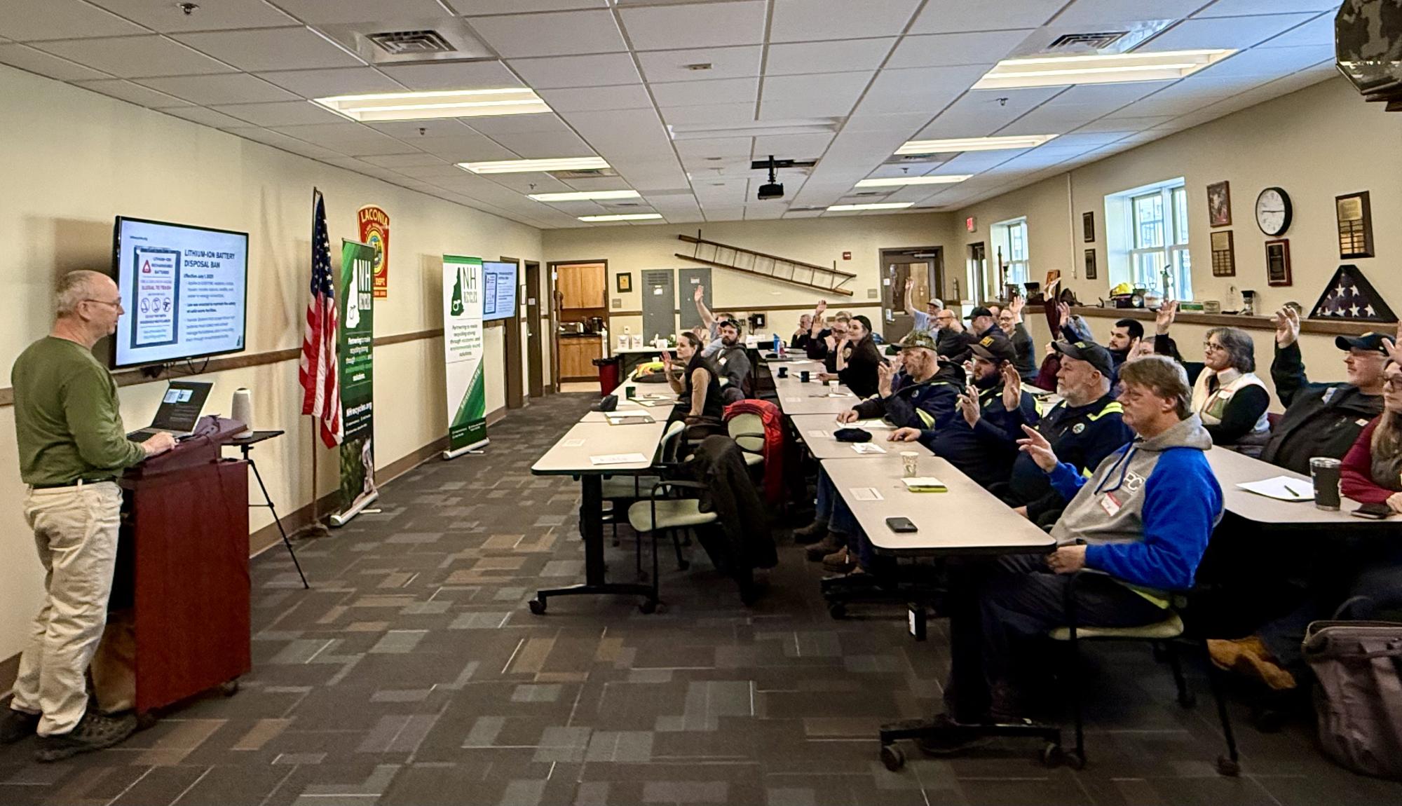 Group participating in a presentation with presenter in green shirt at front of room