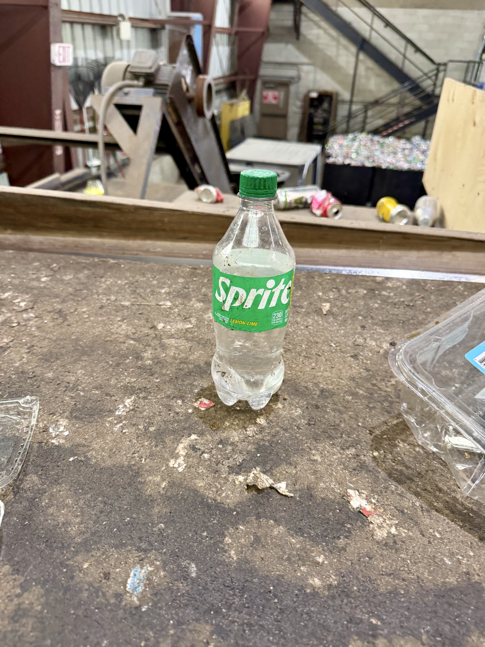 mostly full sprite bottle on a recycling conveyor line