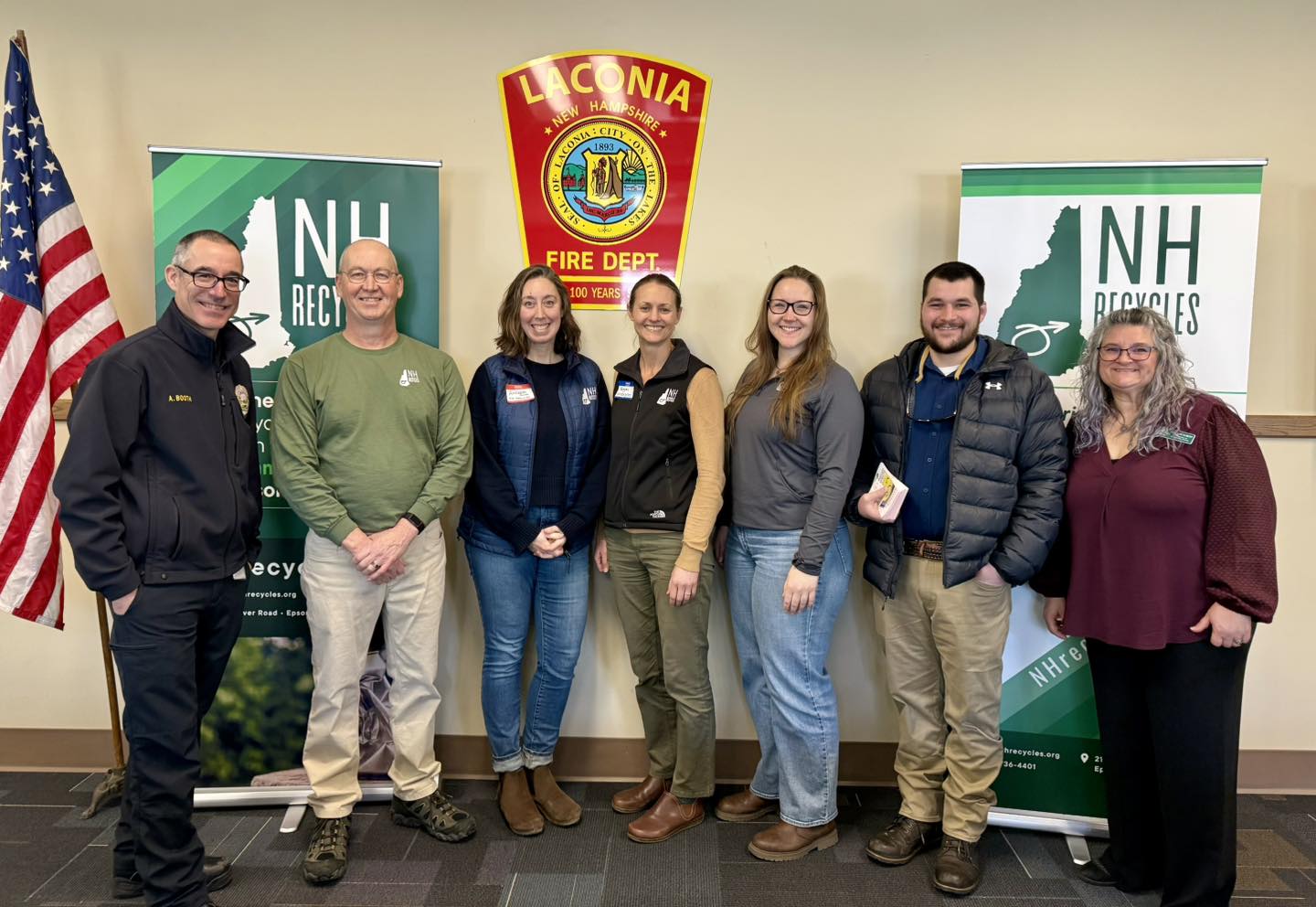 Seven people smiling by two NH Recycles banners
