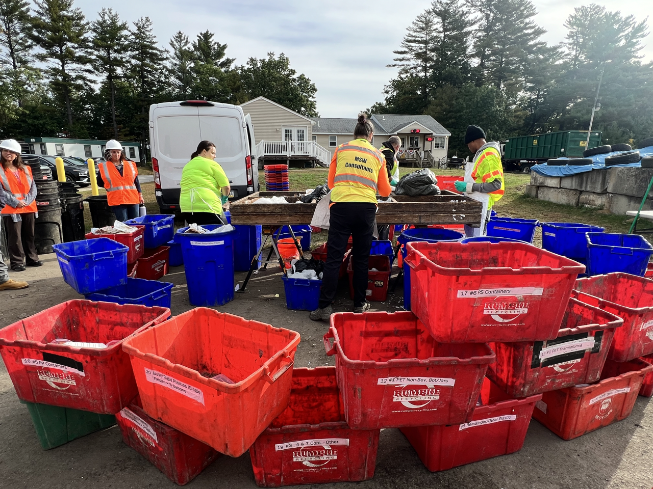 three people sorting trash into 30 red and blue bins