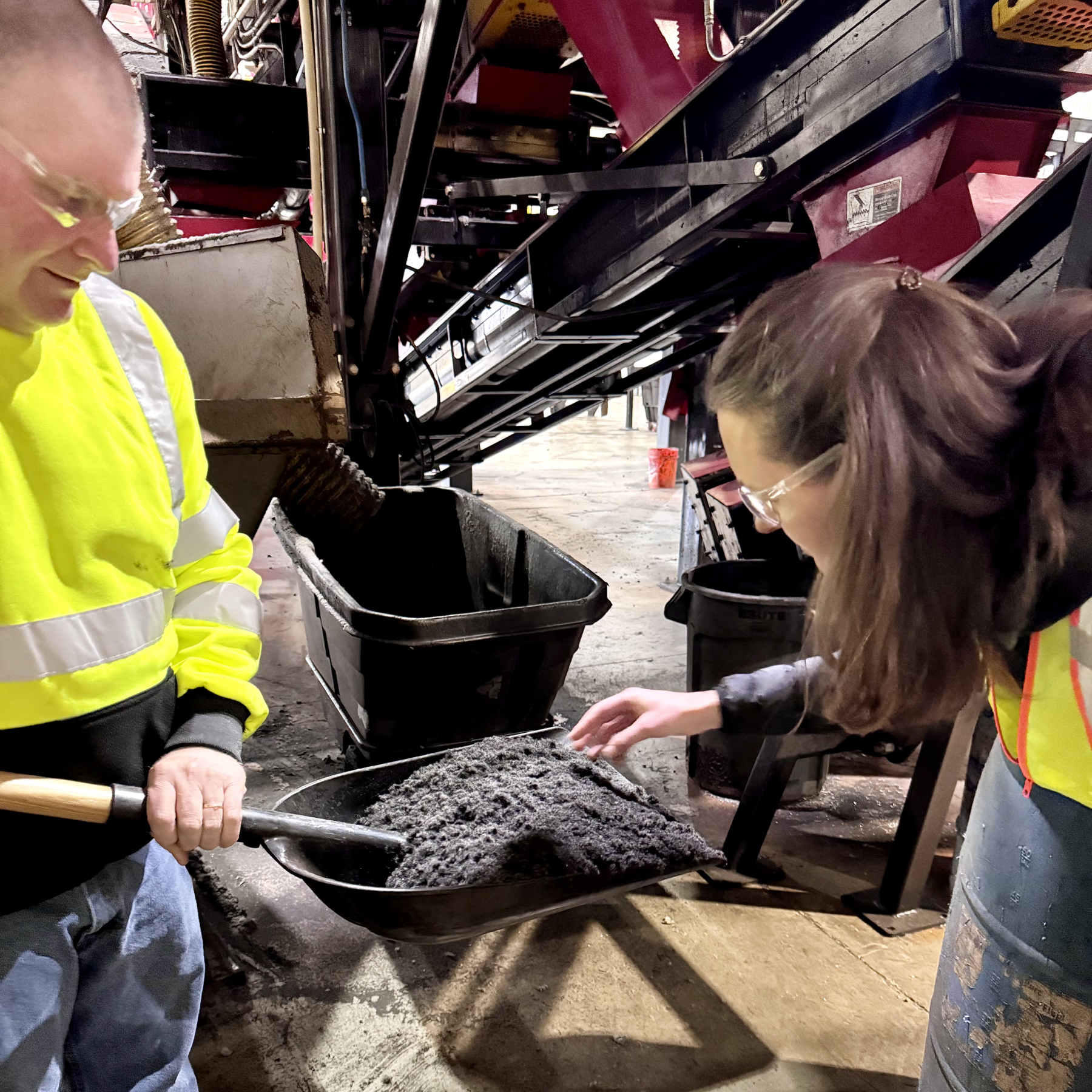 woman looking at black nylon in a shovel held by a man