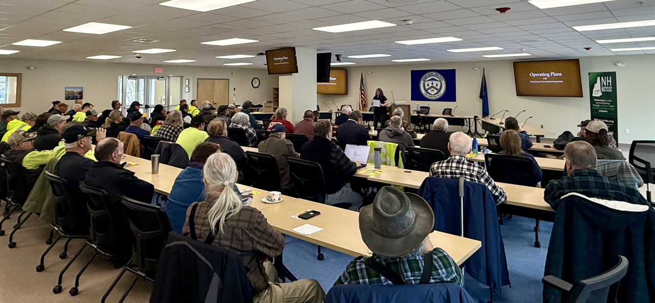 large group of adults in a classroom listening to a woman standing and speaking at the front