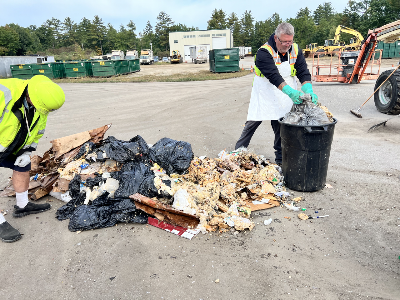 two men sorting through a trash pile