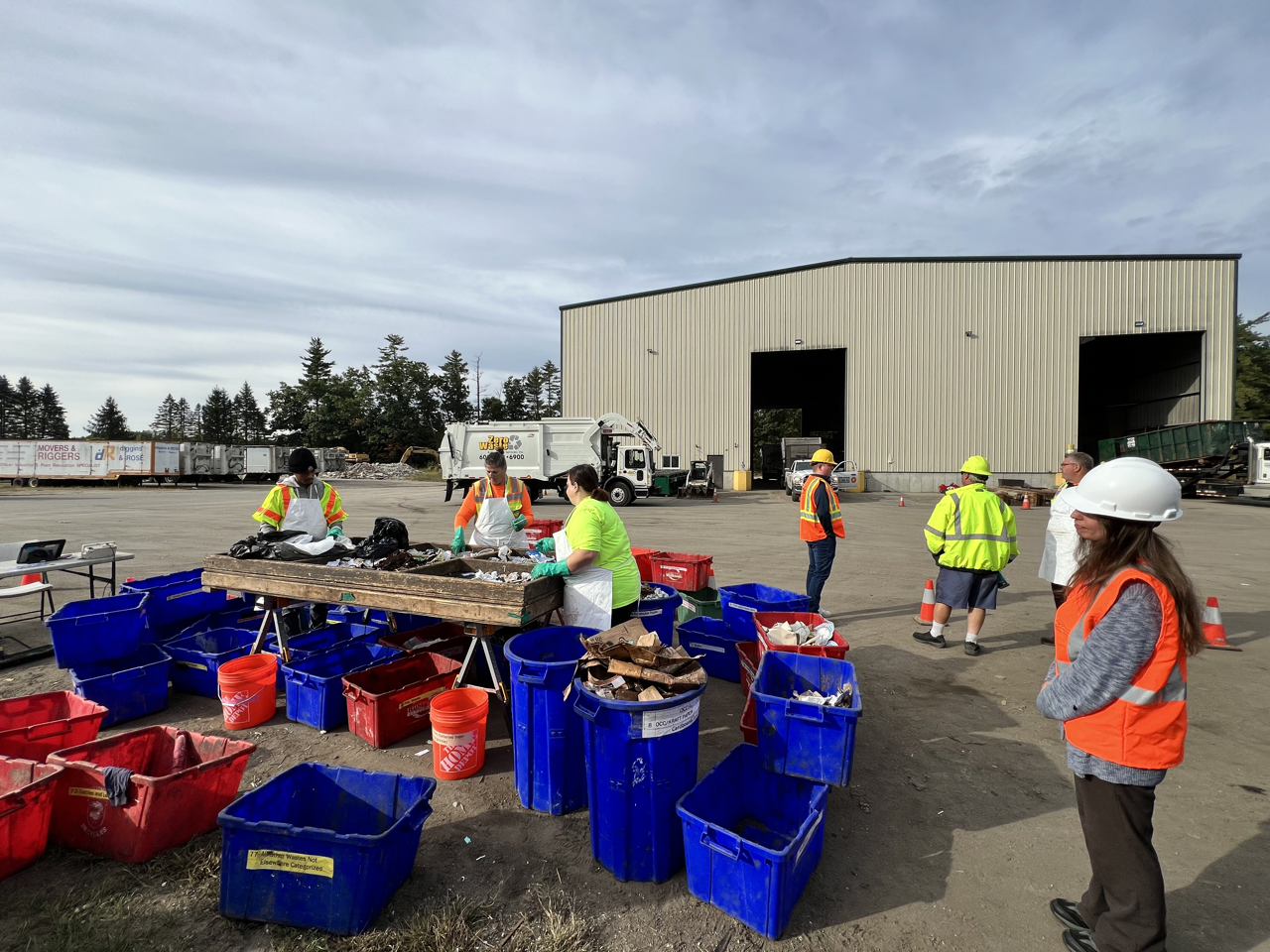 woman watching three people sorting trash into bins