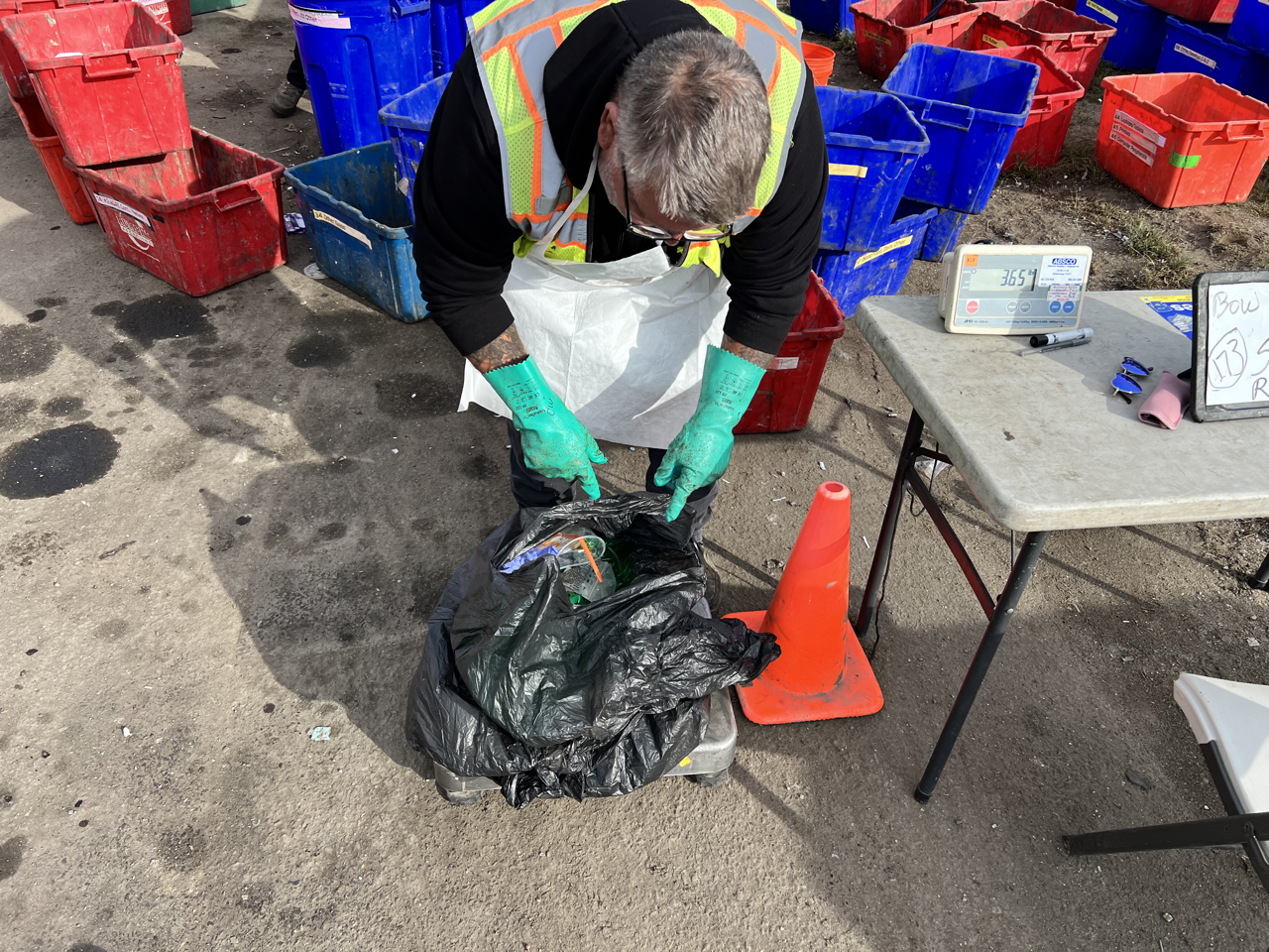 man weighing trash bag on a floor scale