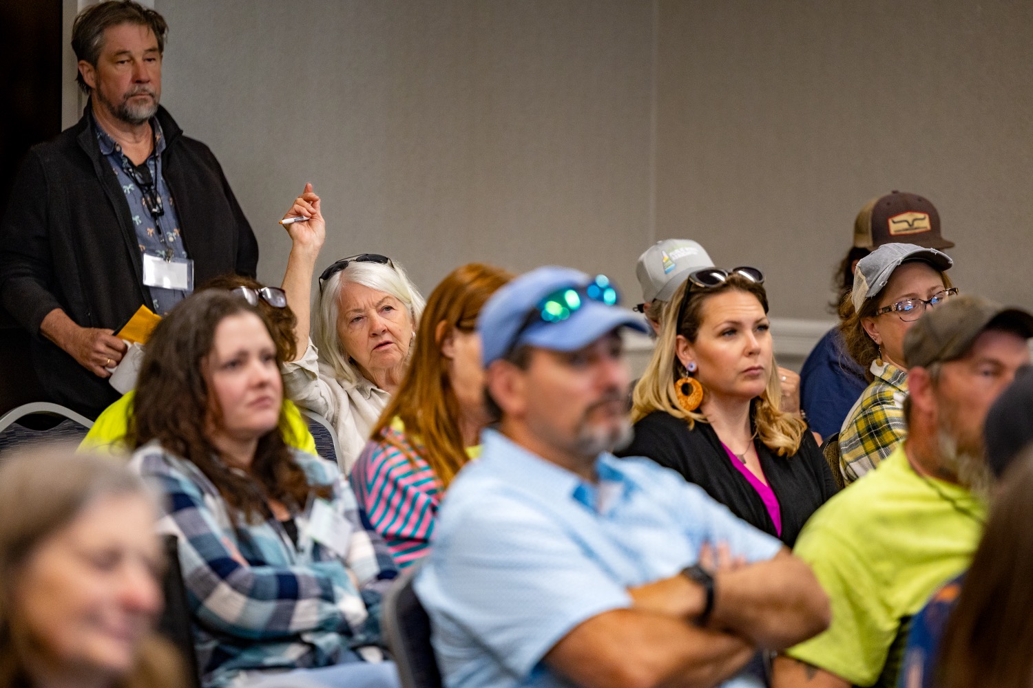 full conference room with woman raising her hand