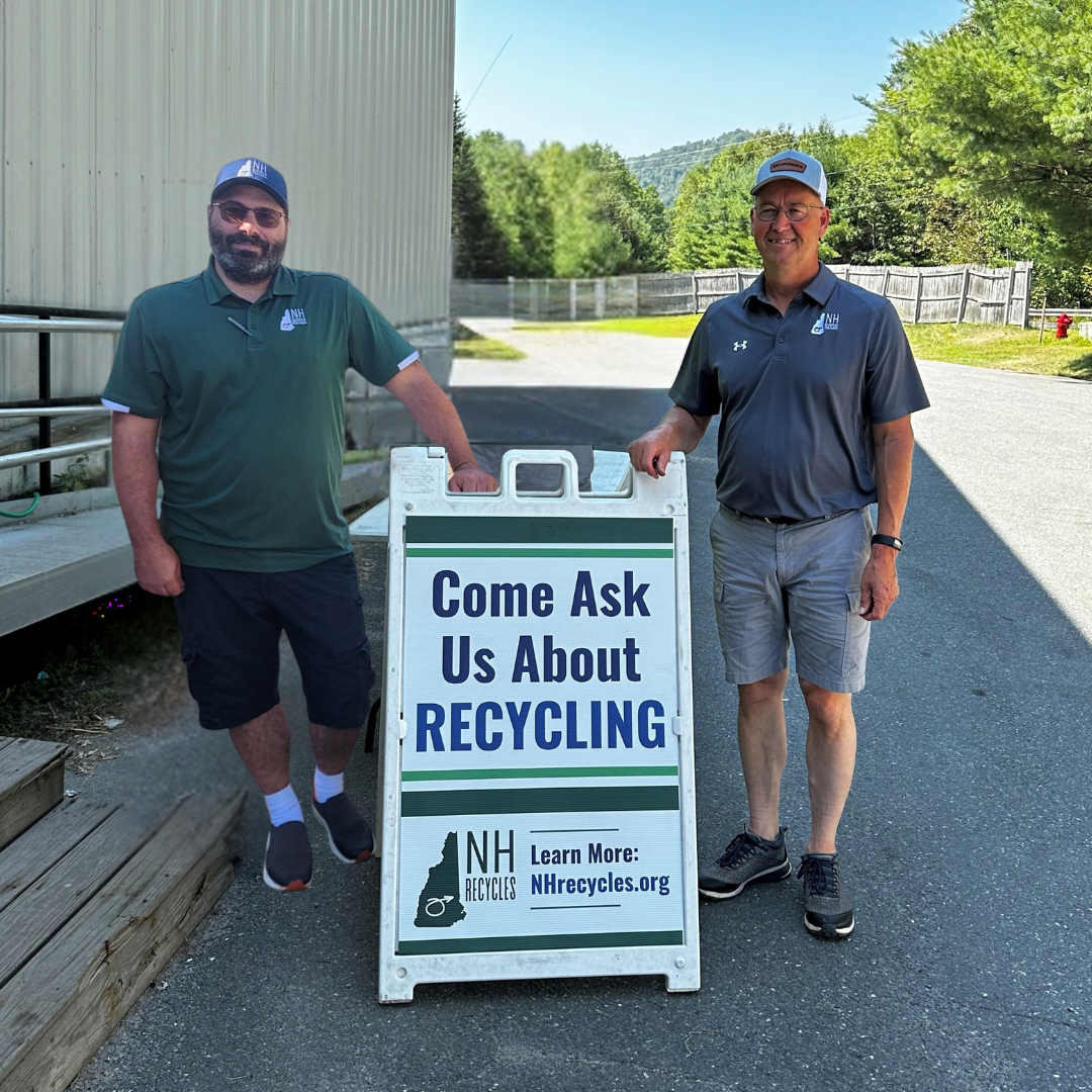 two men standing with a sign that reads Ask Us About Recycling